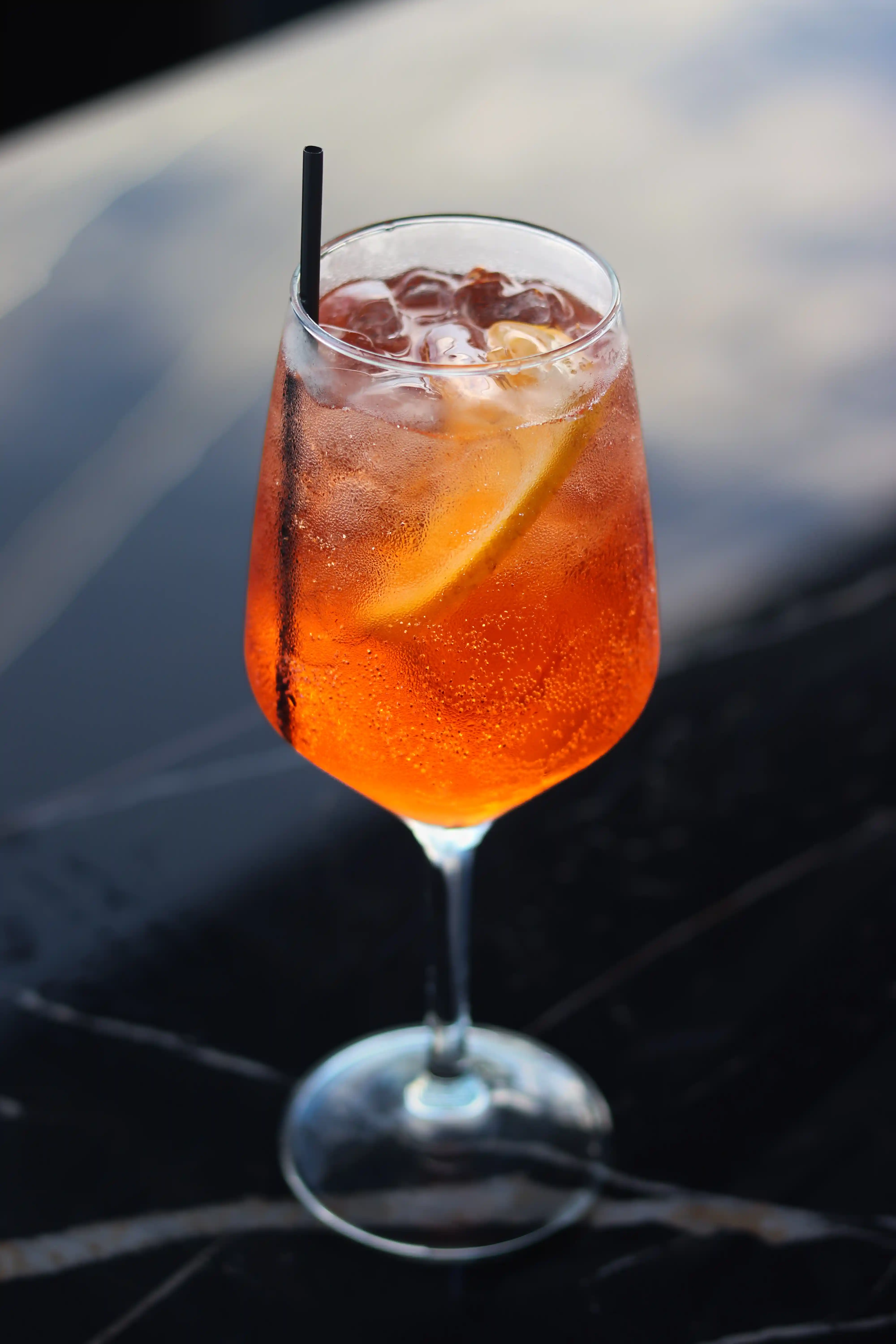 Un refrescante cóctel de naranja con una rodaja de limón, presentado elegantemente en una mesa elegante con un fondo escénico